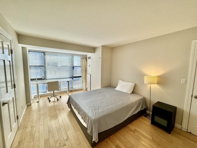 bedroom featuring light wood finished floors and baseboards