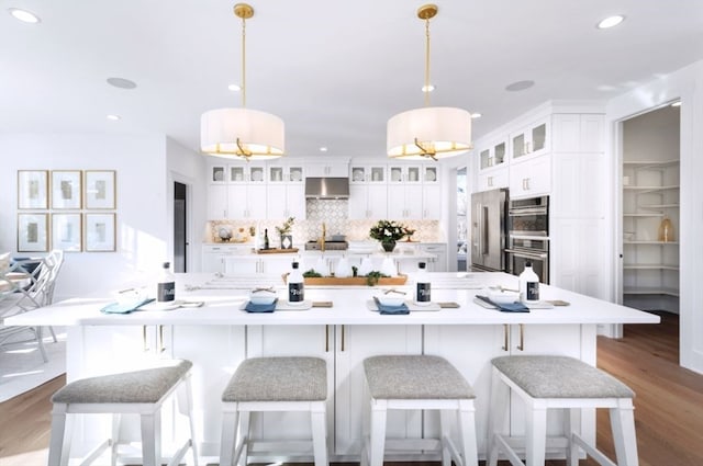 kitchen featuring white cabinets, decorative light fixtures, stainless steel appliances, and extractor fan