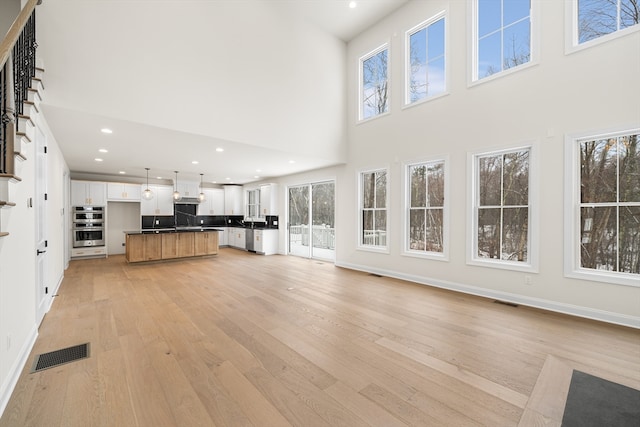 unfurnished living room with a high ceiling and light hardwood / wood-style floors