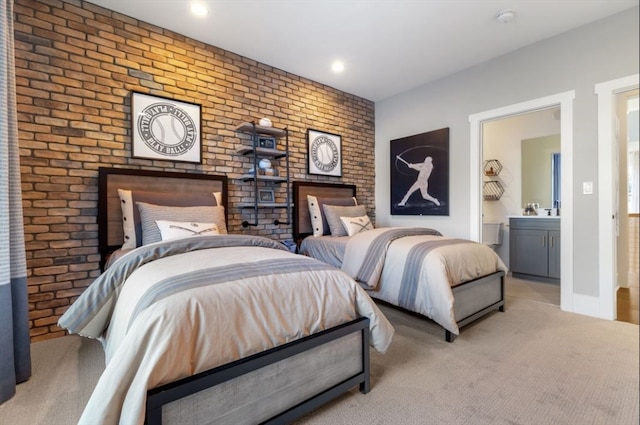 bedroom featuring ensuite bath, light colored carpet, and brick wall