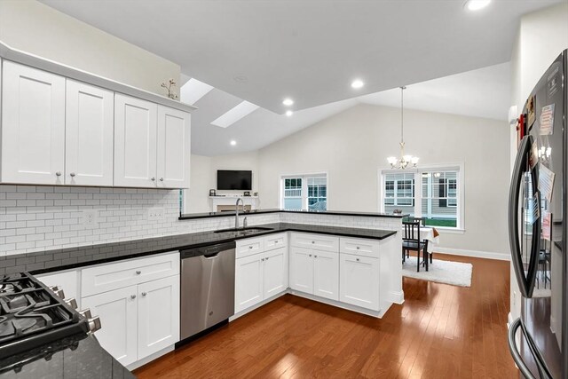 131 Rogerson Xing Unit 131, Uxbridge, MA 01569 - kitchen featuring appliances with stainless steel finishes, a peninsula, a chandelier, decorative backsplash, and dark wood finished floors