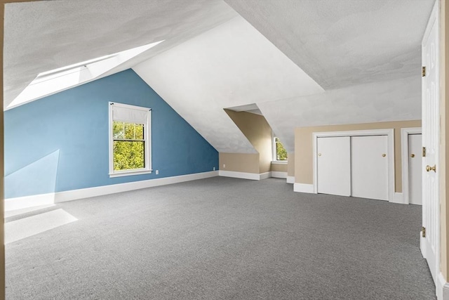 bonus room featuring baseboards, vaulted ceiling, carpet flooring, and a textured ceiling