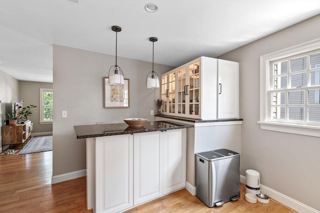 2 Hawthorne Blvd Unit 4, Salem, MA 01970 - kitchen featuring a peninsula, glass insert cabinets, white cabinets, dark stone countertops, and light wood finished floors
