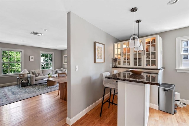 2 Hawthorne Blvd Unit 4, Salem, MA 01970 - kitchen with a kitchen bar, glass insert cabinets, light wood-type flooring, white cabinets, and recessed lighting