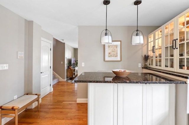 2 Hawthorne Blvd Unit 4, Salem, MA 01970 - kitchen with light wood-type flooring, white cabinetry, decorative light fixtures, glass insert cabinets, and dark stone counters
