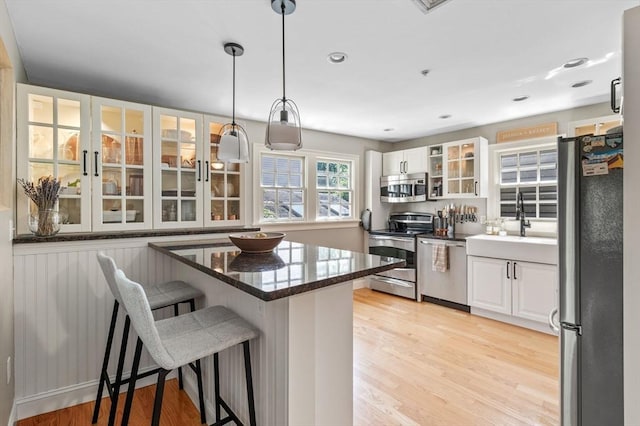 2 Hawthorne Blvd Unit 4, Salem, MA 01970 - kitchen featuring stainless steel appliances, a breakfast bar area, light wood-type flooring, white cabinets, and glass insert cabinets