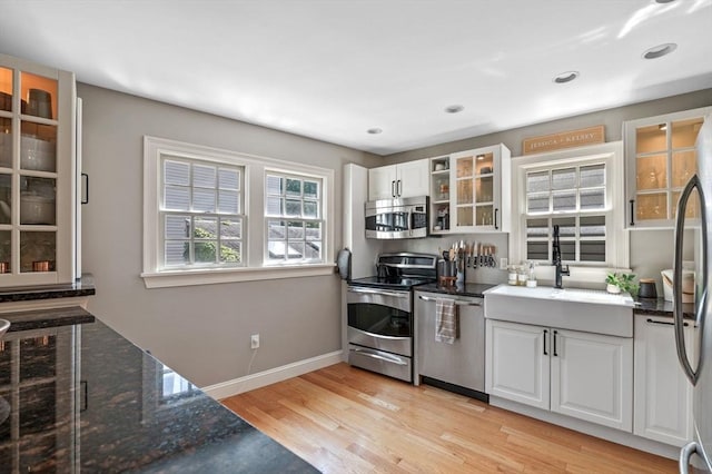 2 Hawthorne Blvd Unit 4, Salem, MA 01970 - kitchen featuring stainless steel appliances, white cabinets, light wood finished floors, glass insert cabinets, and dark stone countertops