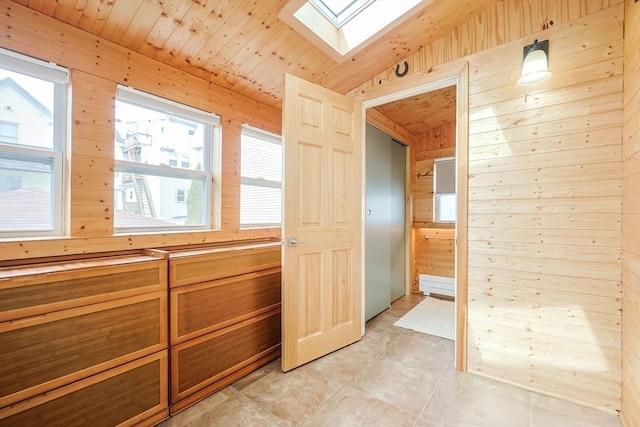corridor with wooden walls, a skylight, vaulted ceiling, light tile patterned floors, and wood ceiling