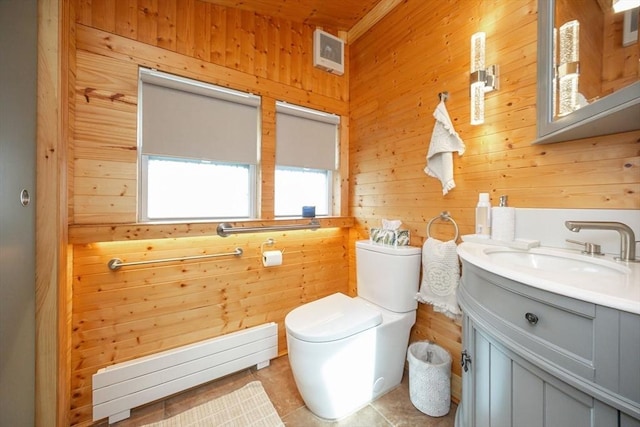 bathroom featuring wooden walls, tile patterned flooring, toilet, vanity, and a baseboard radiator