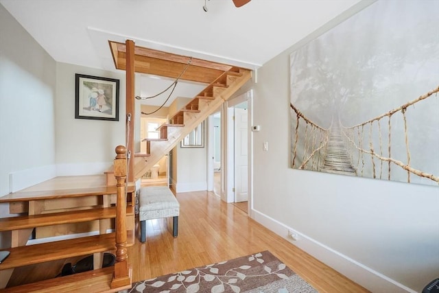 stairway with wood finished floors, baseboards, and ceiling fan