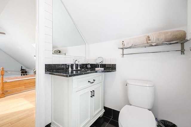 bathroom featuring lofted ceiling, toilet, vanity, and wood finished floors