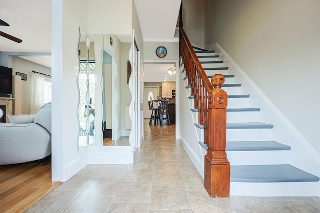 stairway featuring a ceiling fan and baseboards