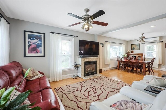living room with a ceiling fan, a fireplace with flush hearth, light wood-style floors, baseboards, and recessed lighting