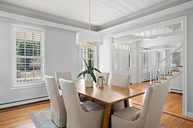 dining area featuring baseboard heating, ornamental molding, wood finished floors, and stairway