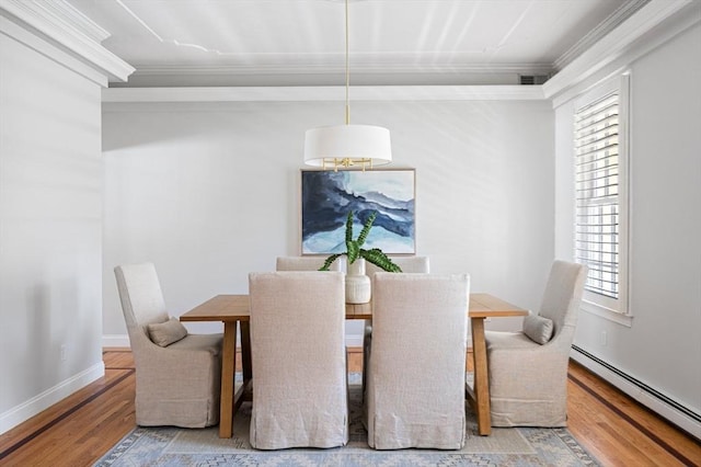 dining area with a baseboard heating unit, baseboards, wood finished floors, and crown molding