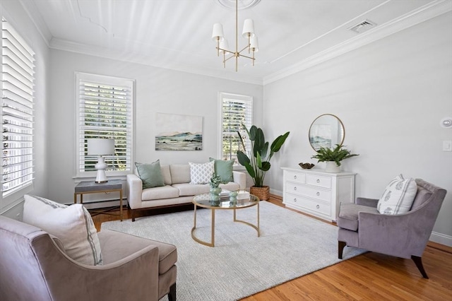 living area with wood finished floors, a chandelier, baseboards, ornamental molding, and visible vents