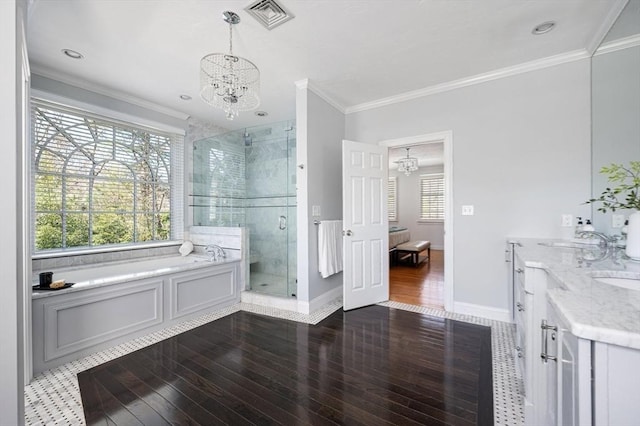 ensuite bathroom featuring a chandelier, wood finished floors, a stall shower, and ornamental molding