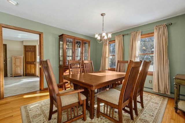 dining area featuring a baseboard radiator, a chandelier, and light wood-type flooring