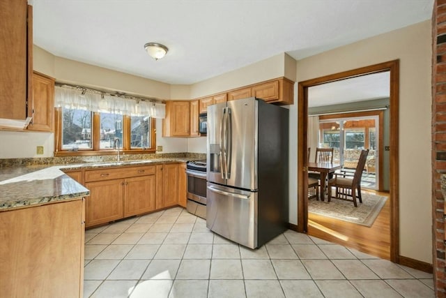 kitchen with dark stone countertops, light tile patterned floors, sink, and appliances with stainless steel finishes