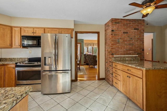 kitchen featuring stainless steel appliances, light tile patterned floors, ceiling fan, and dark stone counters