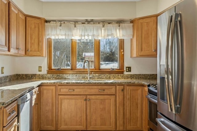 kitchen with appliances with stainless steel finishes, stone countertops, and sink