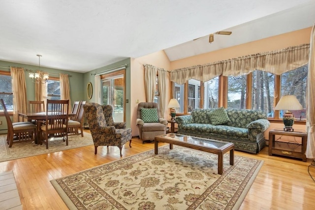 sitting room featuring a notable chandelier, plenty of natural light, vaulted ceiling, and light wood-type flooring