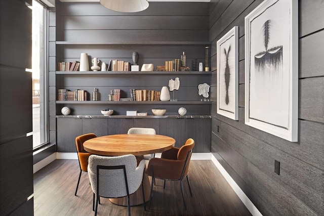 dining space featuring built in features, baseboards, wooden walls, and wood finished floors