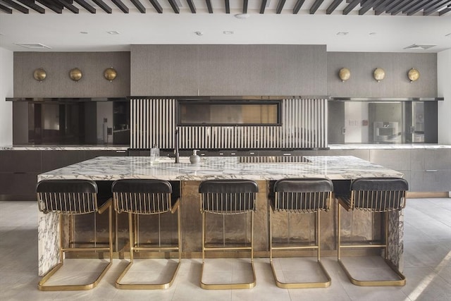 kitchen with light stone counters, visible vents, modern cabinets, and a breakfast bar