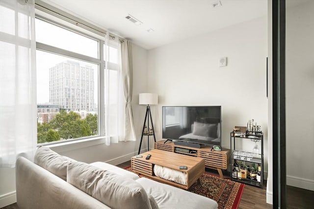 living area featuring a wealth of natural light, visible vents, baseboards, and wood finished floors