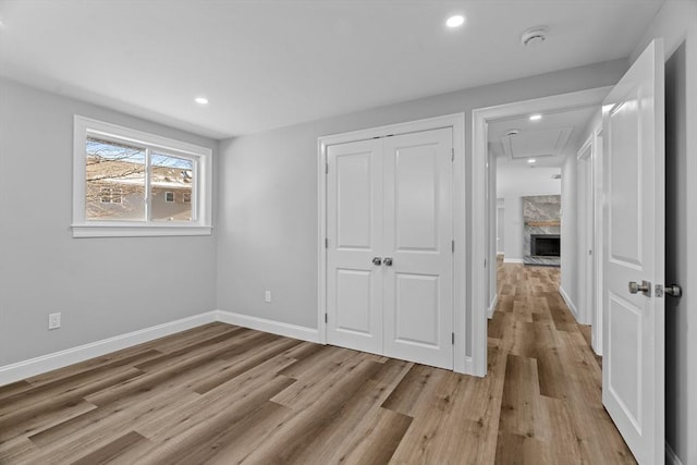 unfurnished bedroom with light wood-type flooring, a closet, and a premium fireplace