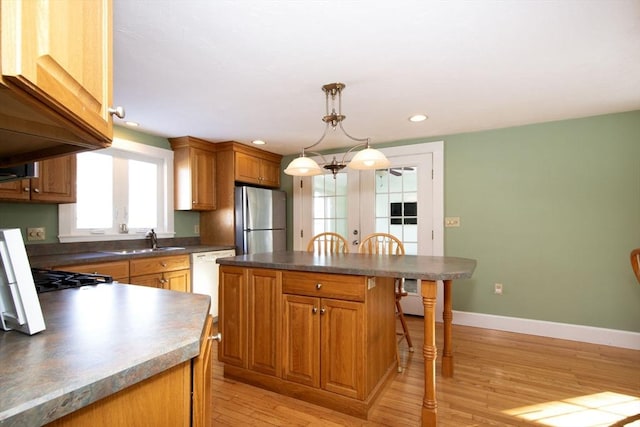 kitchen featuring a center island, sink, stainless steel fridge, light wood-type flooring, and white dishwasher