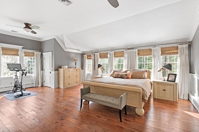 bedroom with visible vents, ornamental molding, vaulted ceiling, and hardwood / wood-style floors