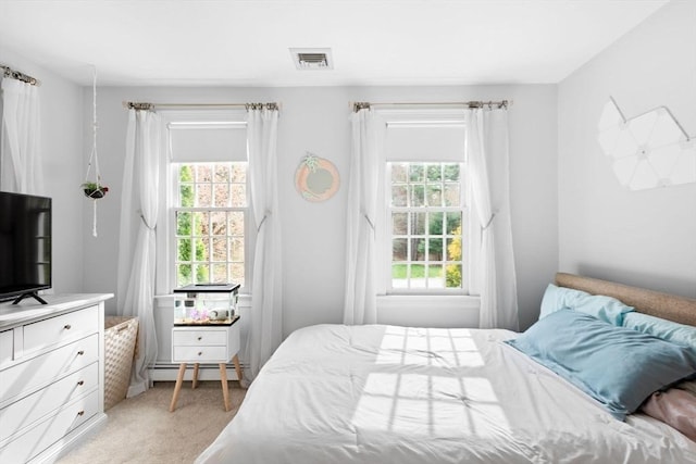bedroom with a baseboard radiator, visible vents, and light colored carpet
