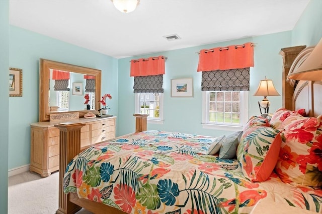 bedroom with baseboards, visible vents, and light carpet
