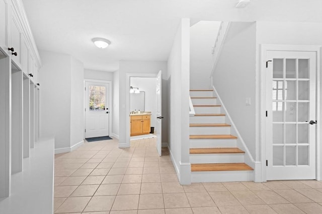 interior space featuring stairs, baseboards, and light tile patterned floors