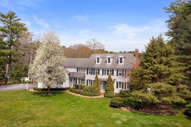 view of front facade with a chimney and a front lawn