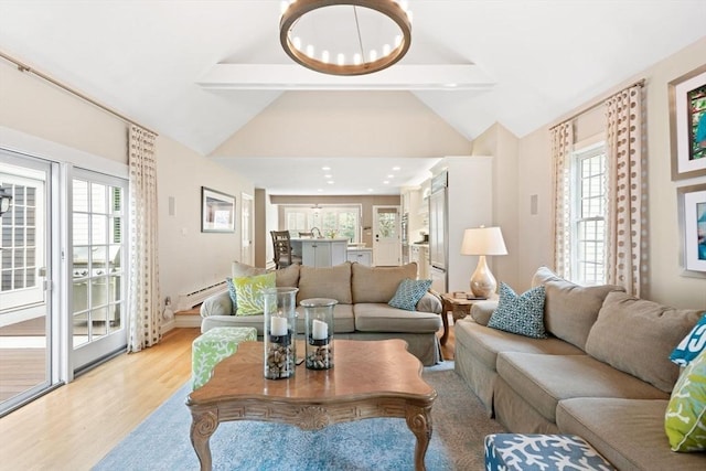 living room featuring plenty of natural light, a baseboard radiator, light wood finished floors, and lofted ceiling