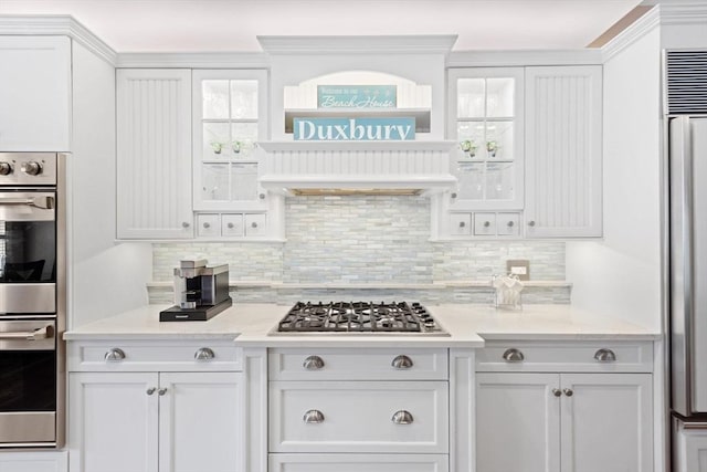 kitchen with white cabinets, stainless steel appliances, decorative backsplash, and glass insert cabinets