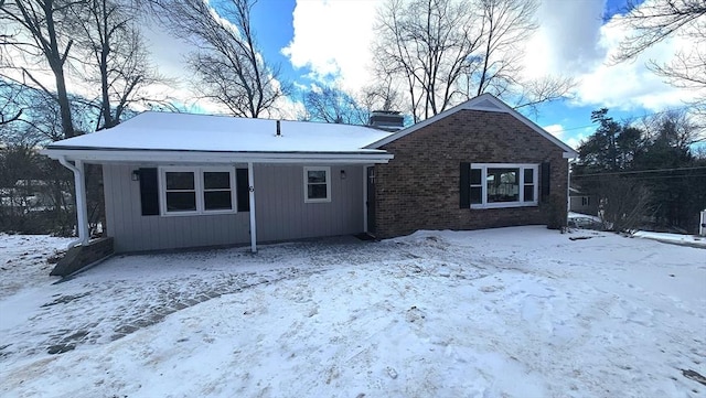 view of front of home with a chimney and brick siding