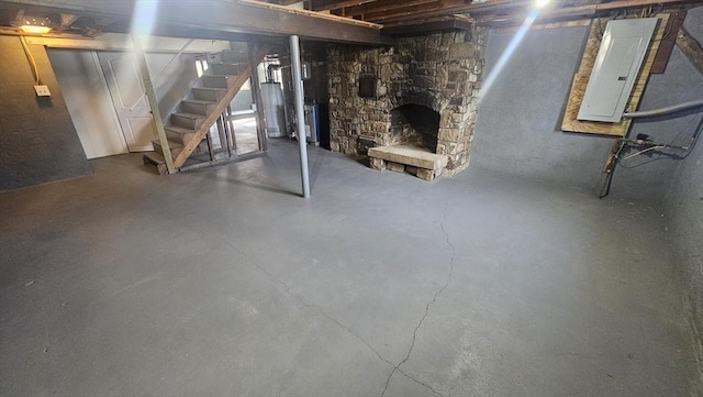 unfinished basement featuring water heater, a stone fireplace, stairs, and electric panel