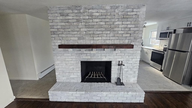 room details featuring white cabinets, electric stove, wood finished floors, freestanding refrigerator, and a baseboard heating unit