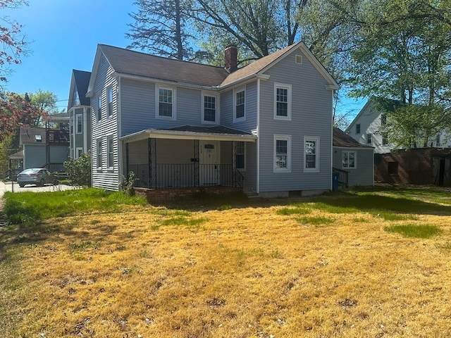 view of front facade featuring a porch, a front lawn, and a chimney