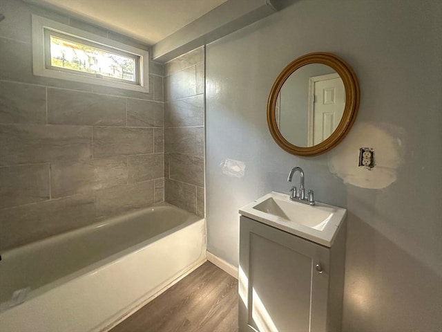 bathroom featuring baseboards, bathing tub / shower combination, wood finished floors, and vanity
