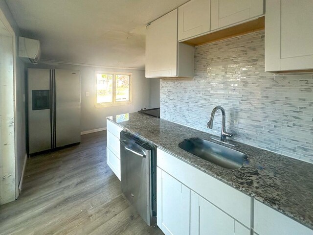 kitchen featuring light wood-type flooring, white cabinets, tasteful backsplash, a sink, and appliances with stainless steel finishes