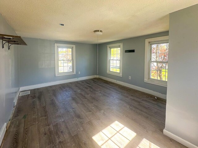 spare room featuring baseboards, a textured ceiling, and wood finished floors