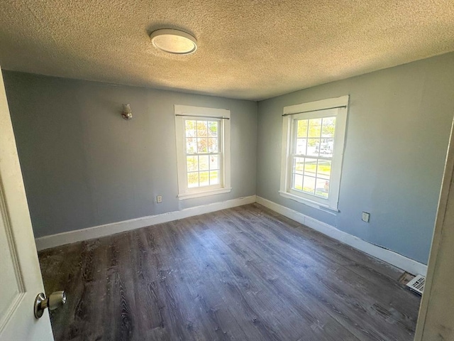 spare room featuring baseboards, a textured ceiling, wood finished floors, and a healthy amount of sunlight