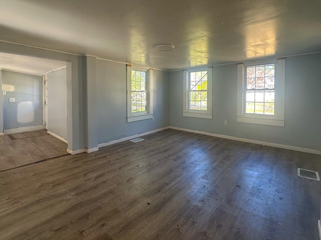spare room featuring baseboards, dark wood-type flooring, and visible vents