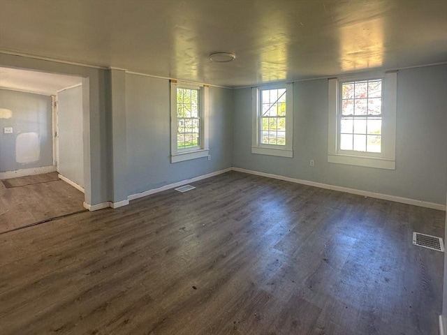 unfurnished room featuring visible vents, baseboards, and dark wood-type flooring