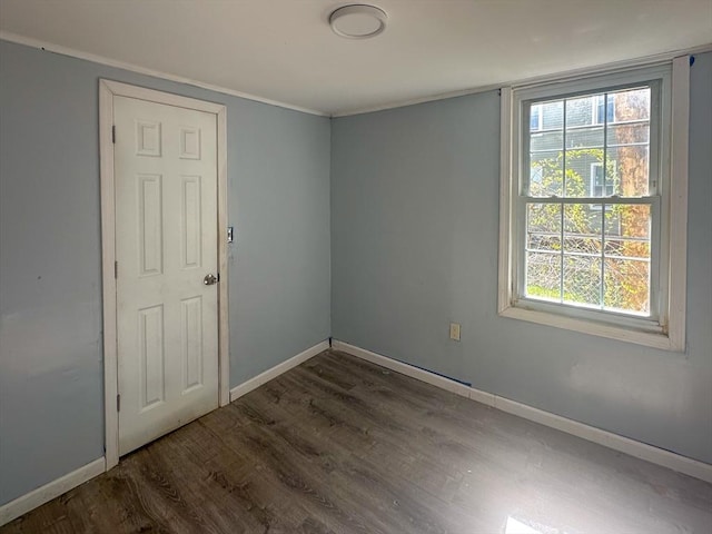 unfurnished room featuring baseboards, crown molding, and wood finished floors
