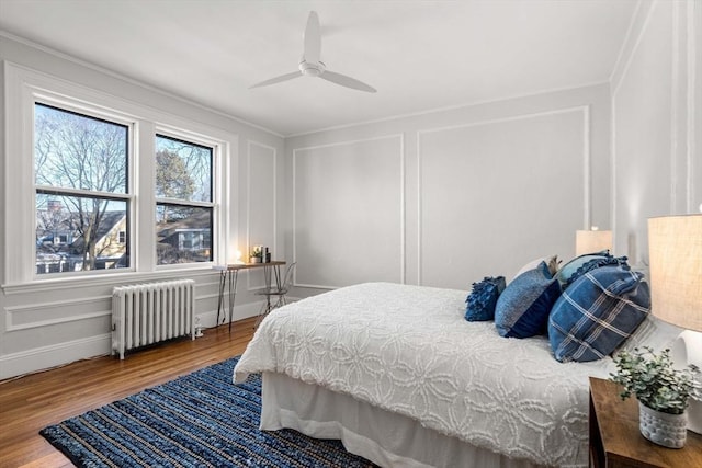 bedroom with radiator, hardwood / wood-style floors, and ceiling fan